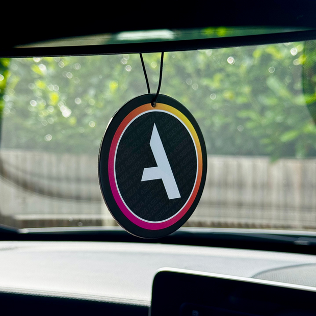 Car air freshener with a logo hanging from the rearview mirror.