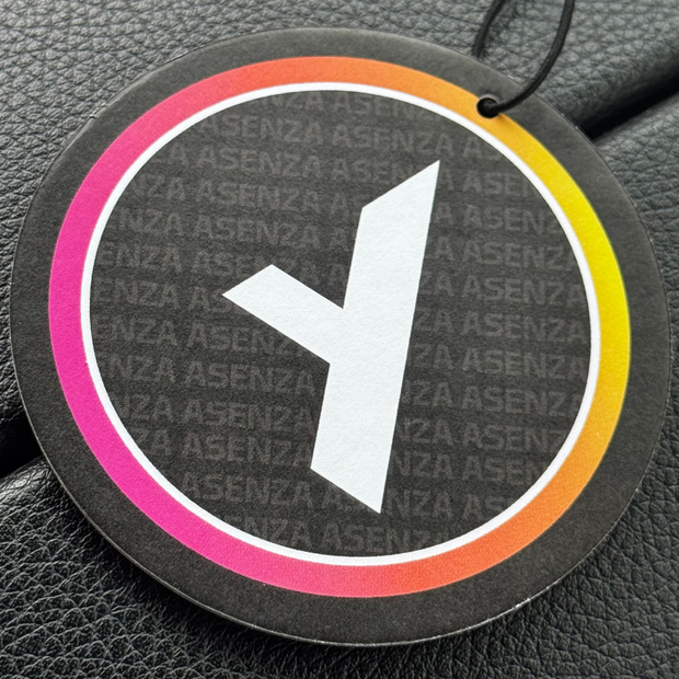 Round air freshener with colorful rim and brand name on a textured surface